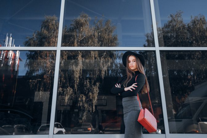 Brunette Girl Standing proud in front of Tinted Windows of a Commercial Building